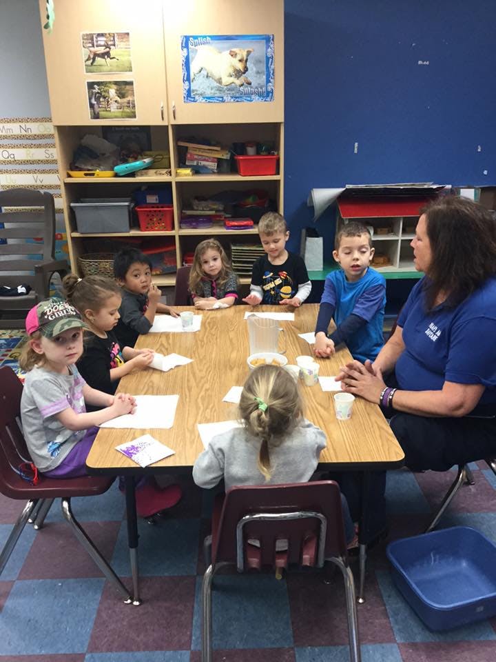Adult and children sitting around a table in a classroom