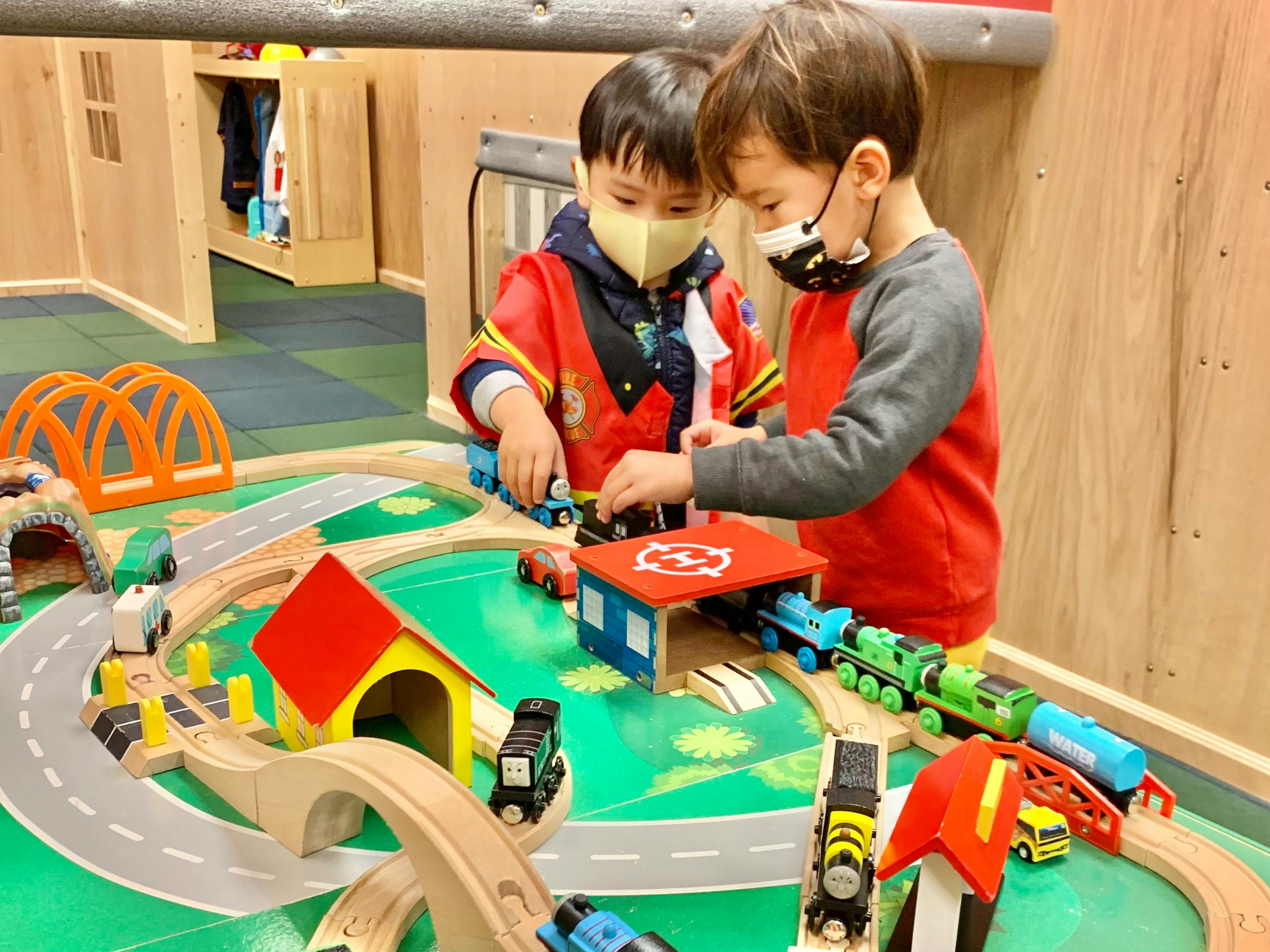 Two children playing with a toy train set