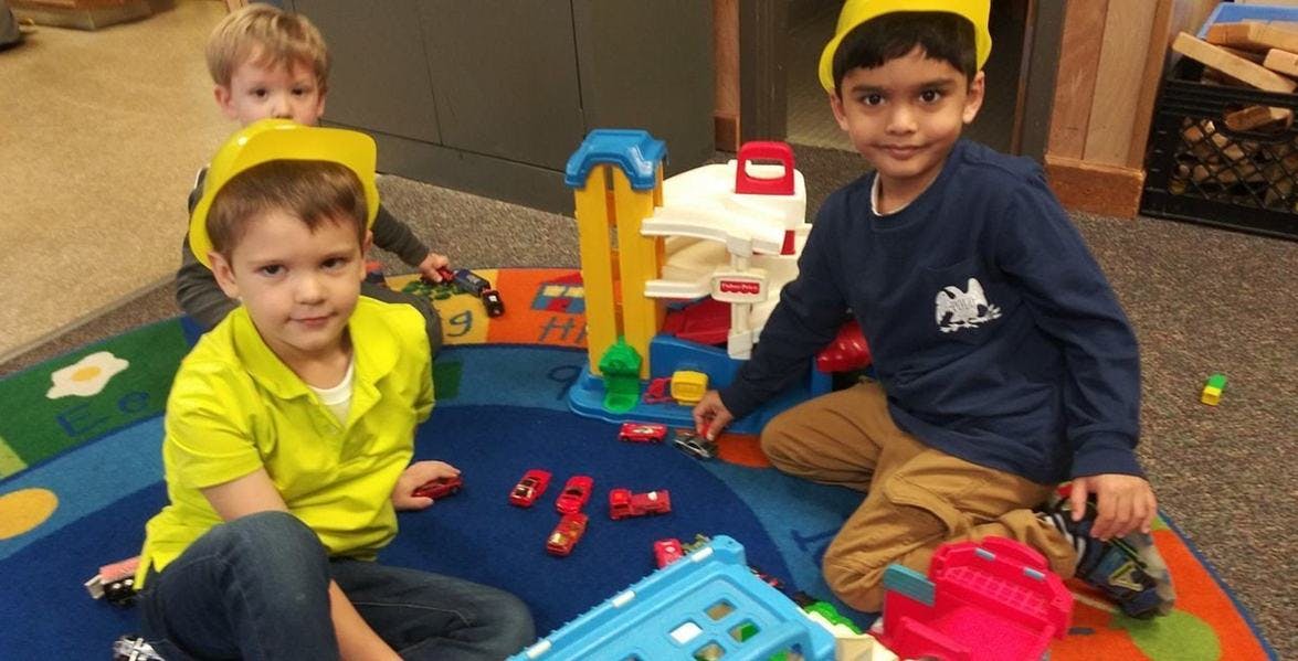 Three children playing with toy cars and a toy garage