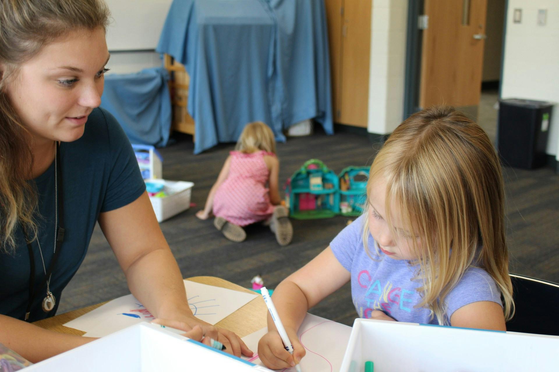 Person and child drawing at a table