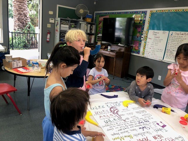 Children gathered around a table with a large paper