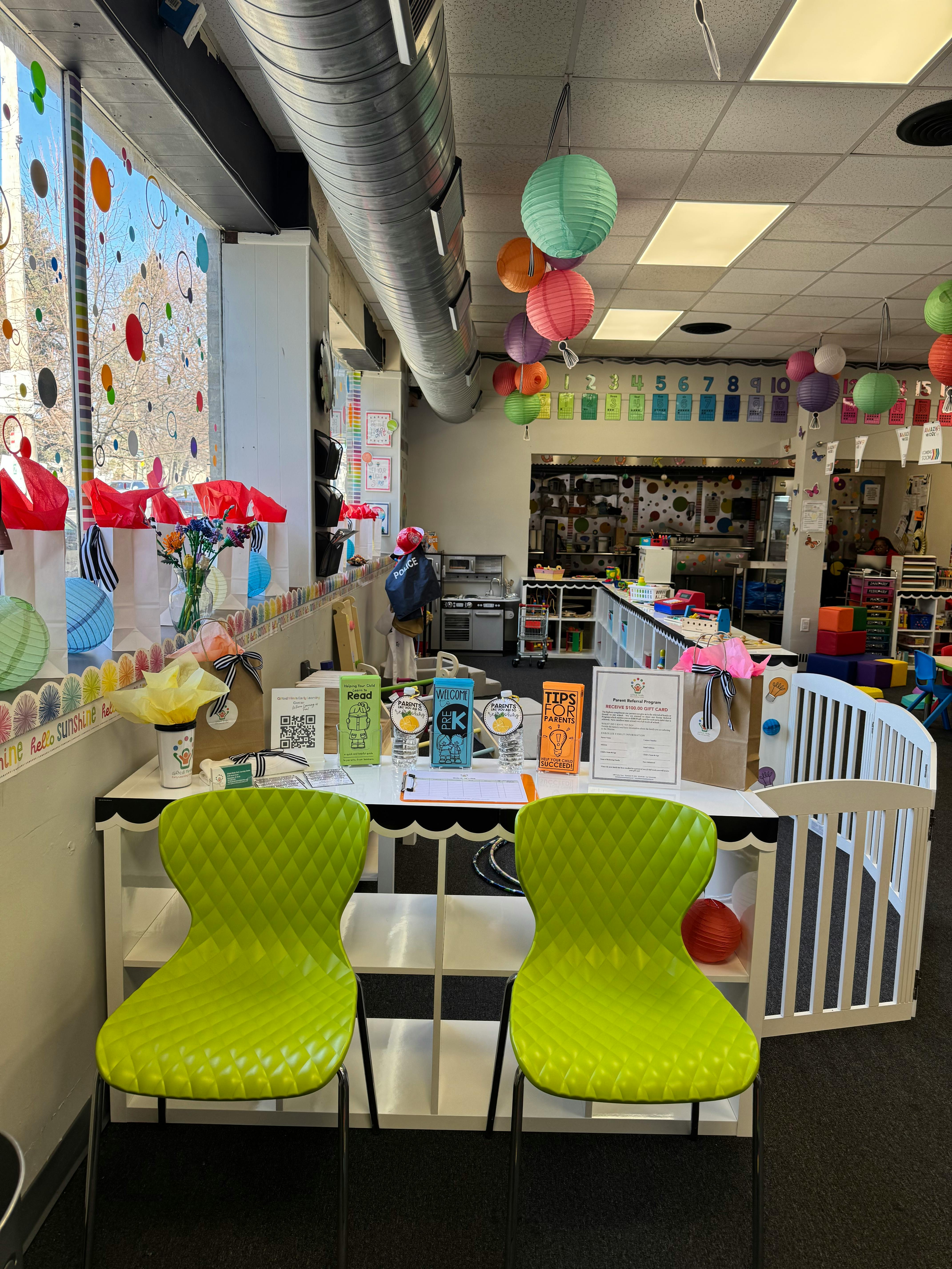 Two green chairs in front of a table with items in a classroom