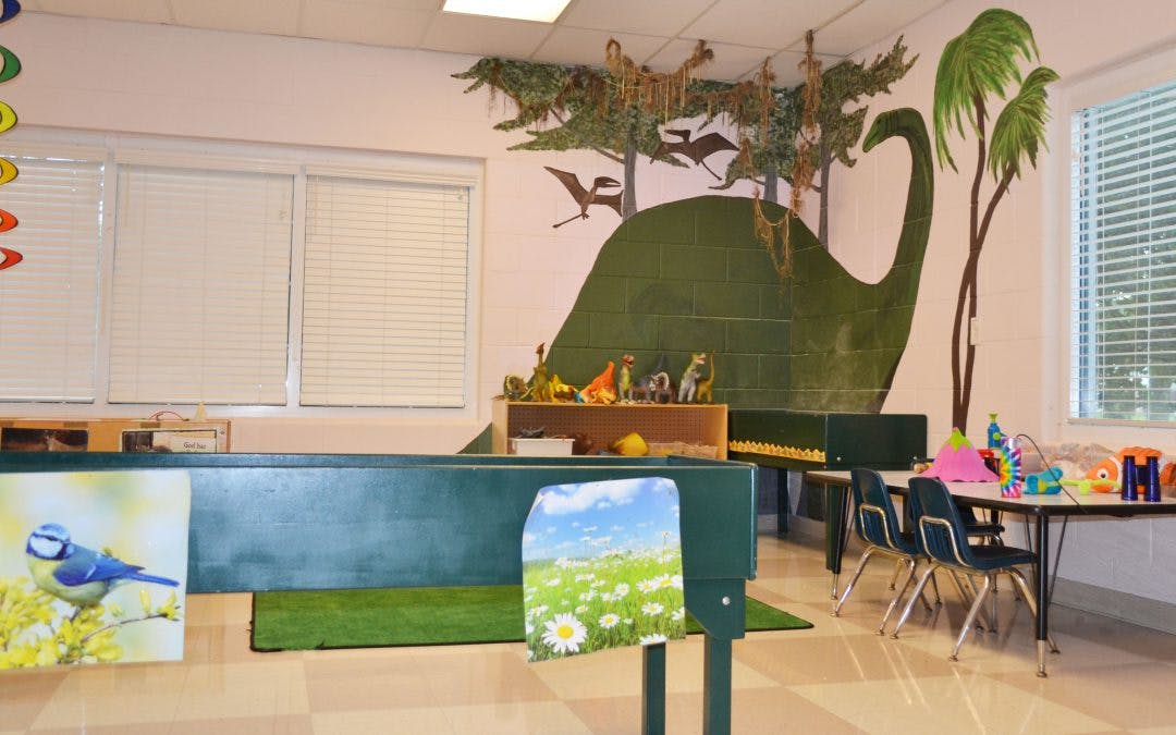Classroom with dinosaur mural and small tables