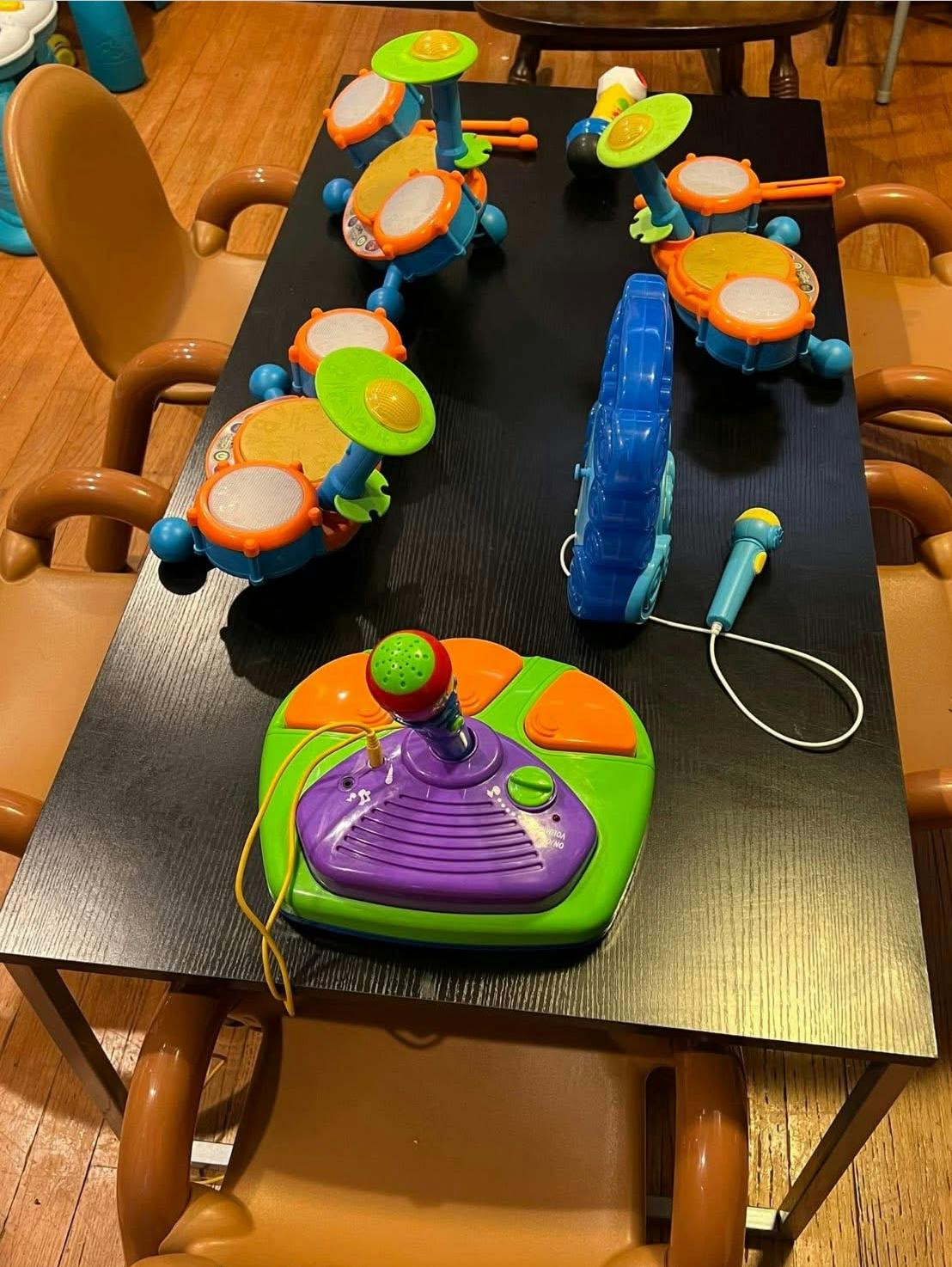 Children's toy instruments on a table, including drums, a guitar, and a microphone