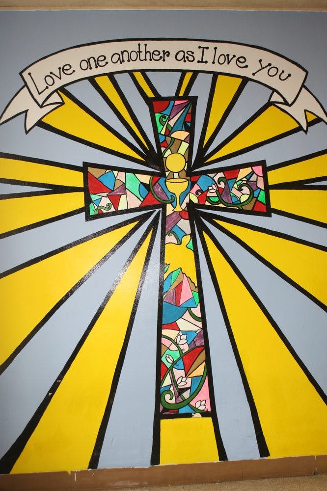Mural of a stained glass cross with sun rays and a banner with text