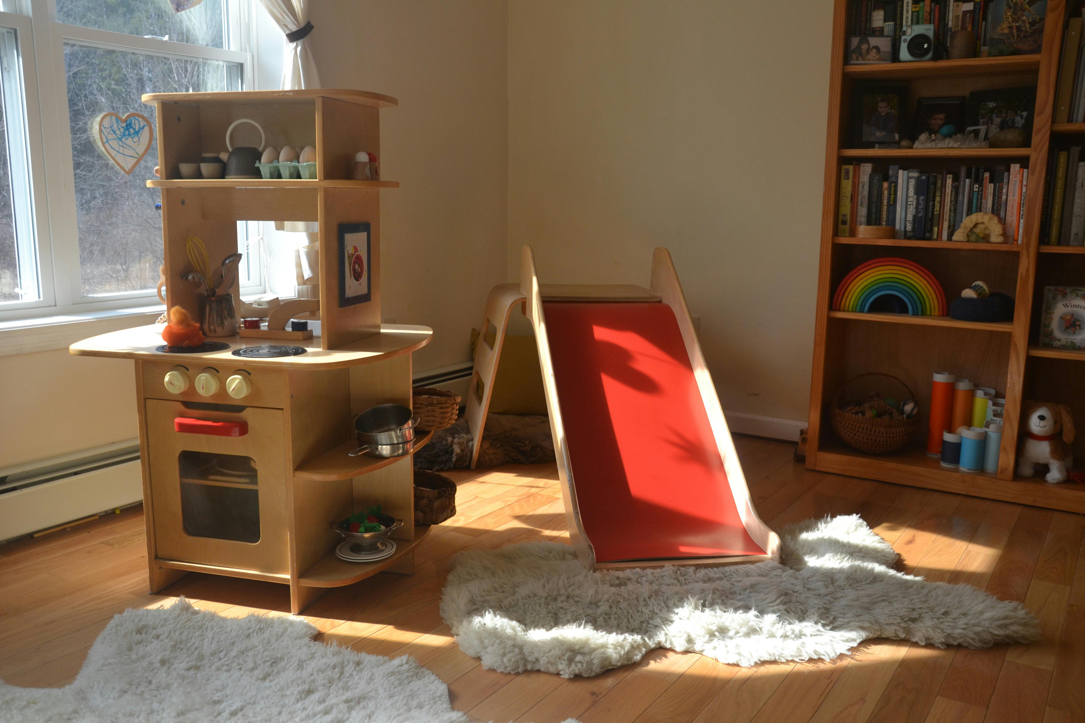 Toy kitchen and red slide in a room