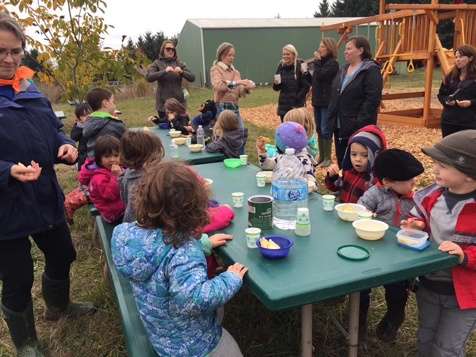 Adults and children gathered around picnic tables outdoors