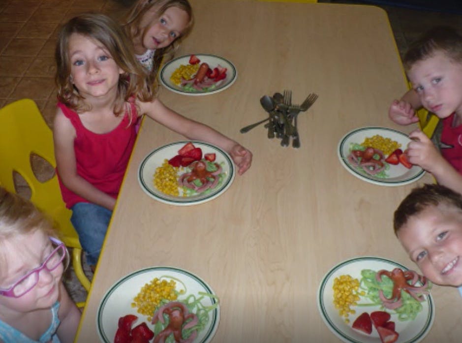 Children sitting around a table with plates of food