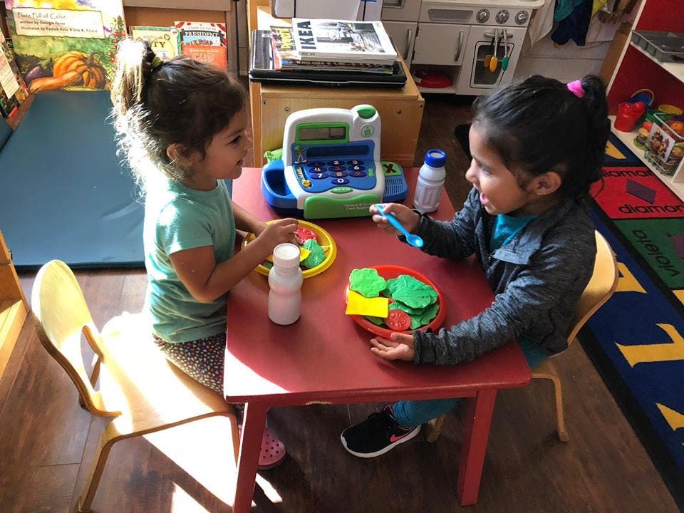 Two children playing with toy food at a small table