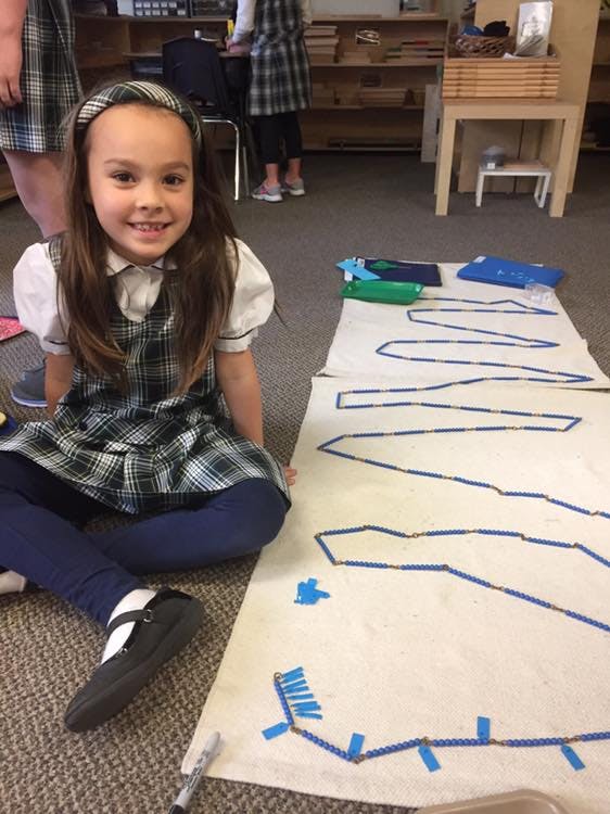 Child sitting on floor next to a long paper with blue shapes