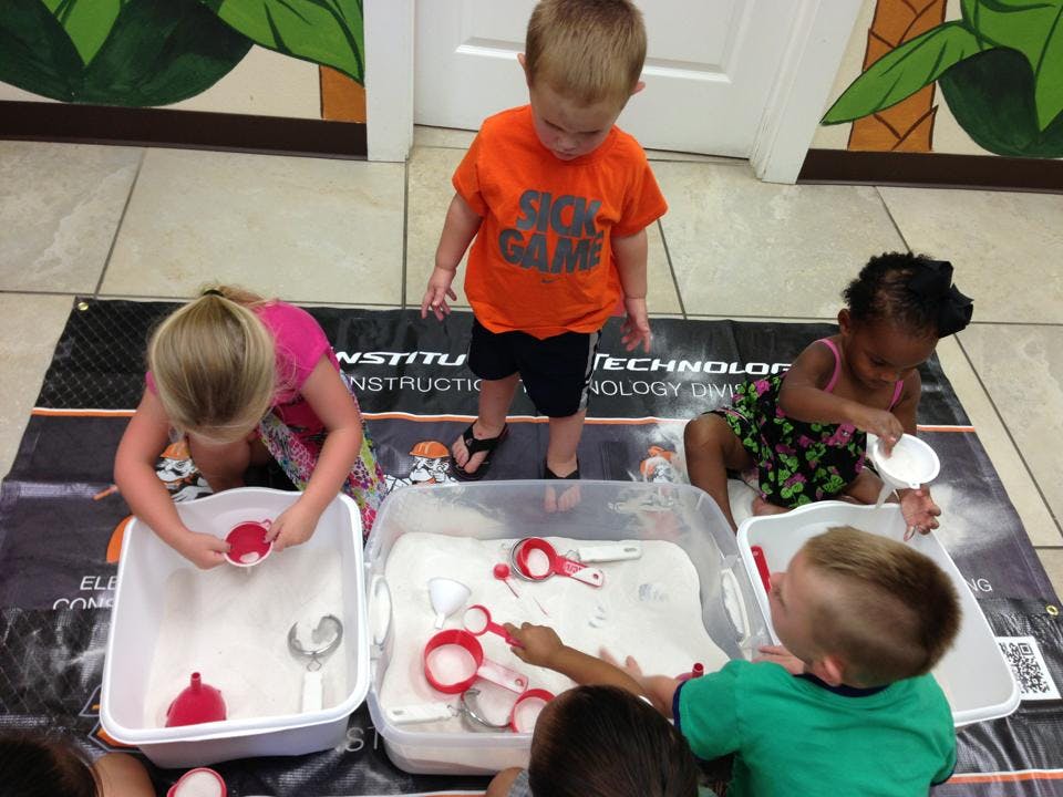Children playing with sand and scoops in containers