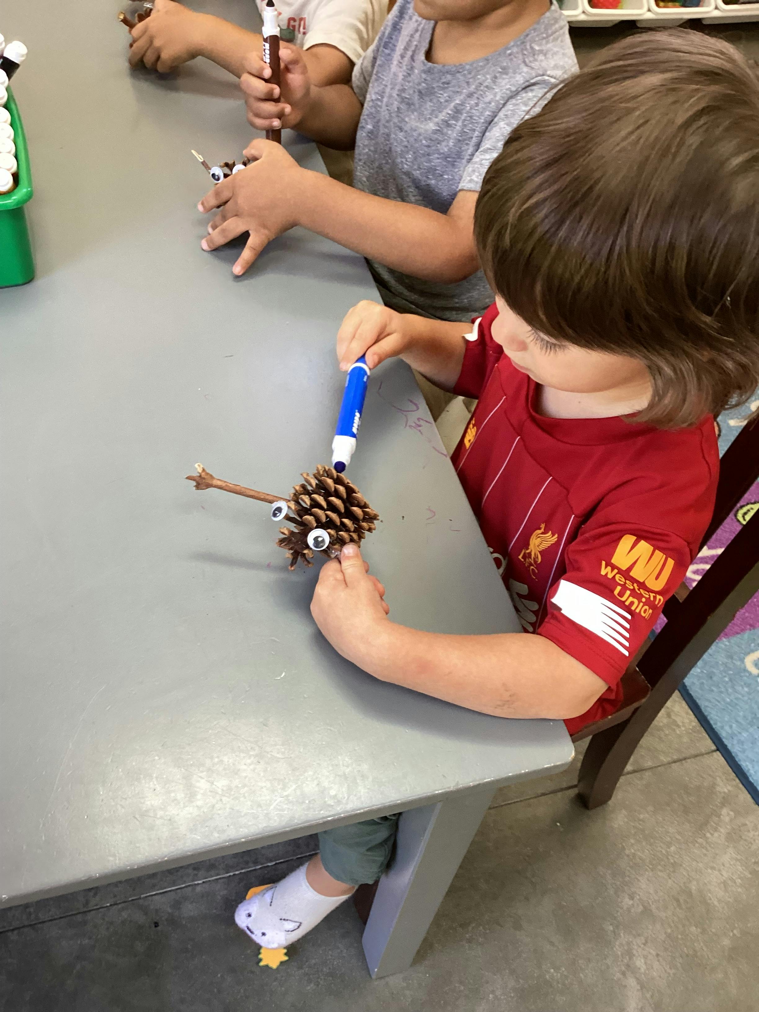 Children crafting animals from pinecones at a table
