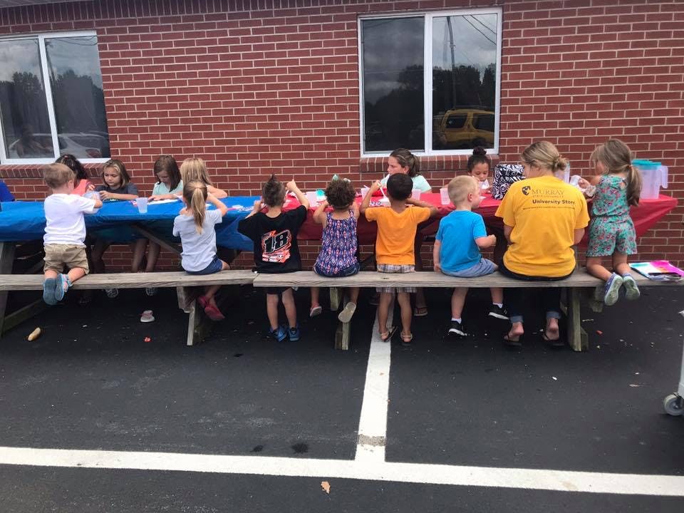 Children and adults sitting at a picnic table outdoors