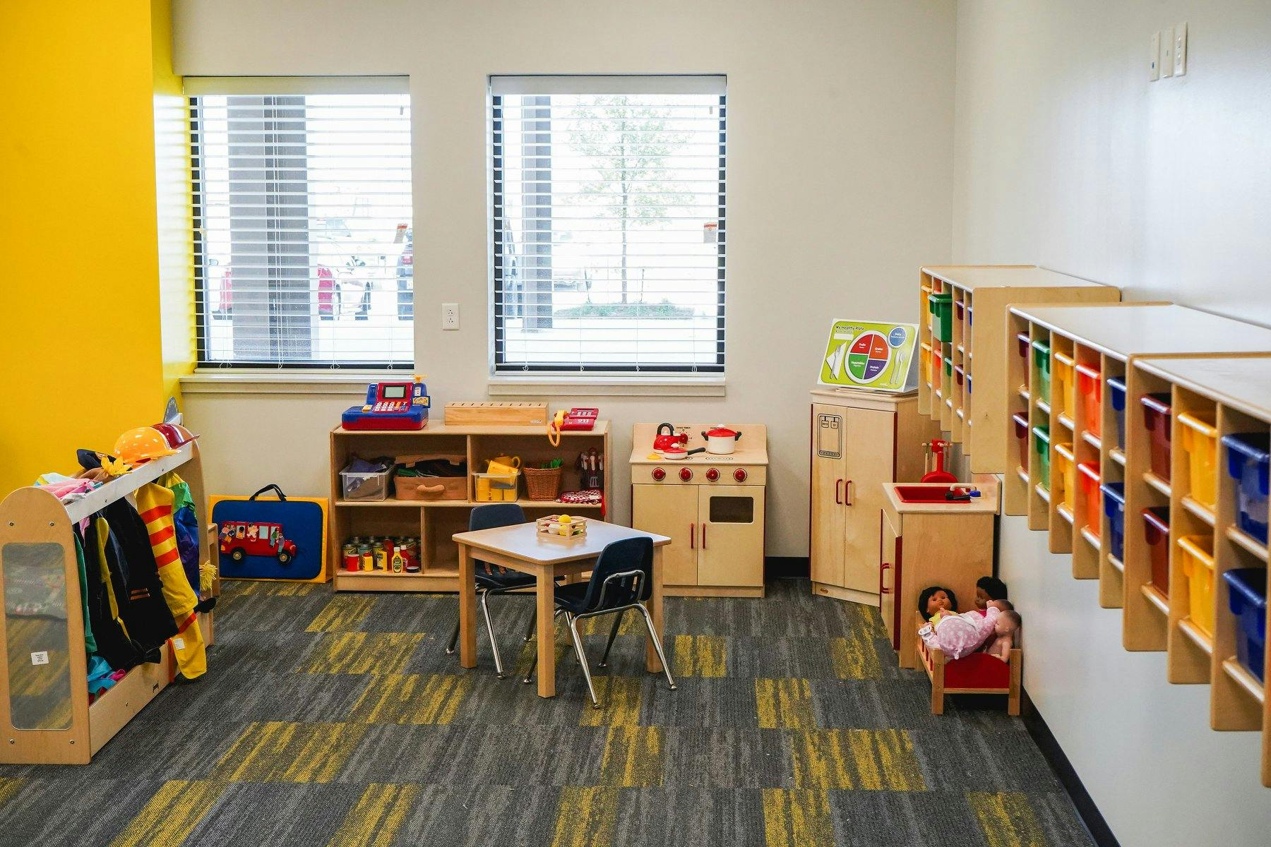 Classroom with small table and chairs, play kitchen, and storage shelves