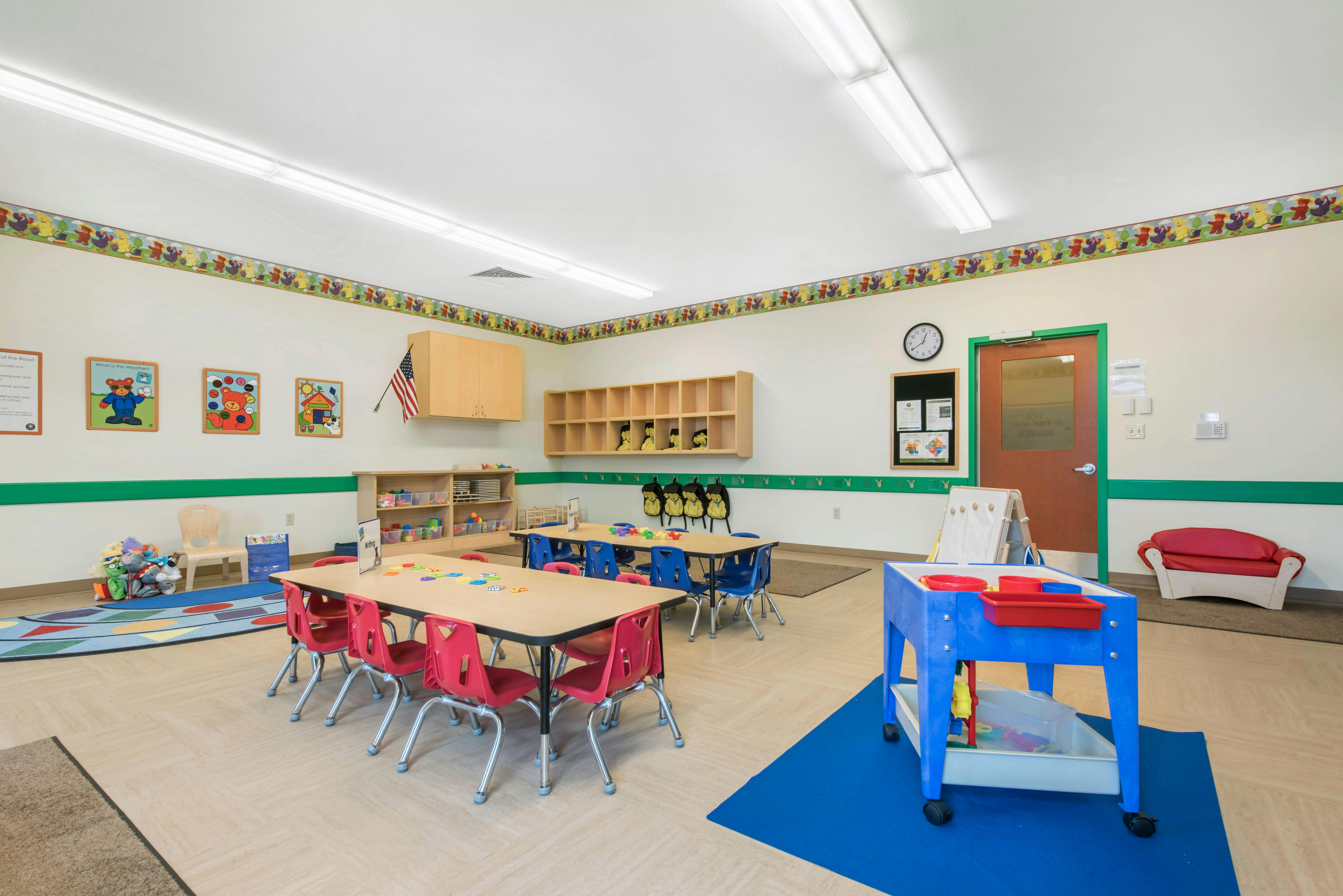 Classroom with child-sized tables and chairs, shelves, and learning materials