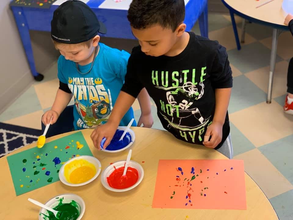 Two children painting with colorful paints and vibrant paints