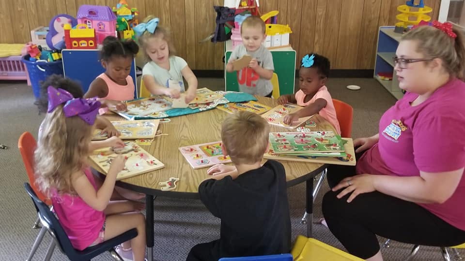 Adult and children sitting at a table with puzzles