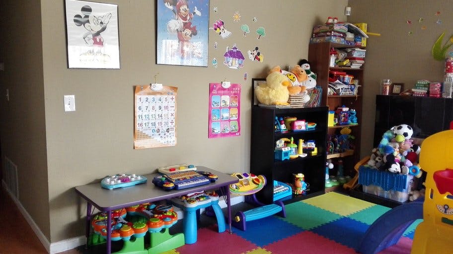 Playroom with a small table, shelves of toys, and colorful floor mats