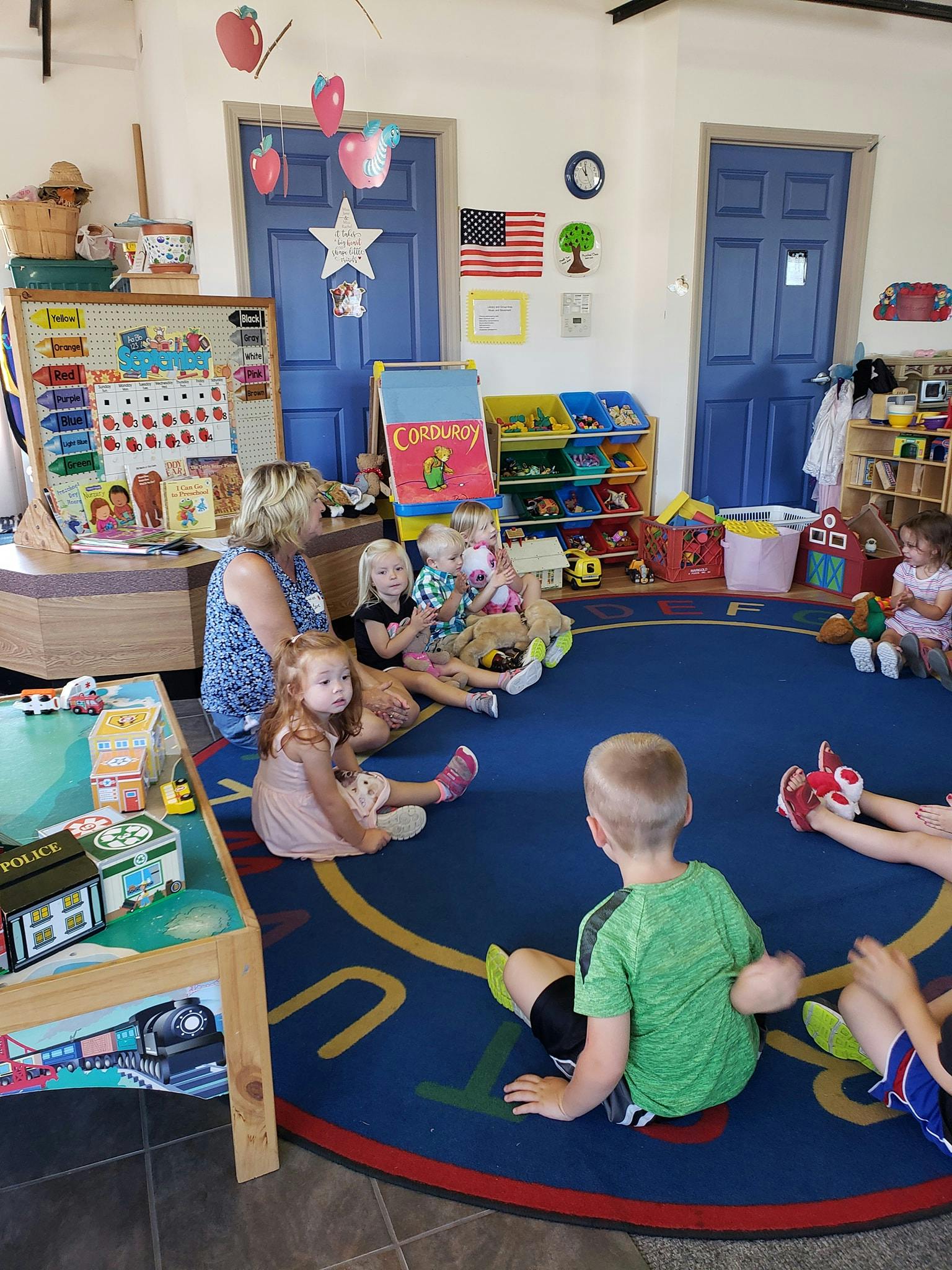 Adult and children sitting on a rug in a classroom