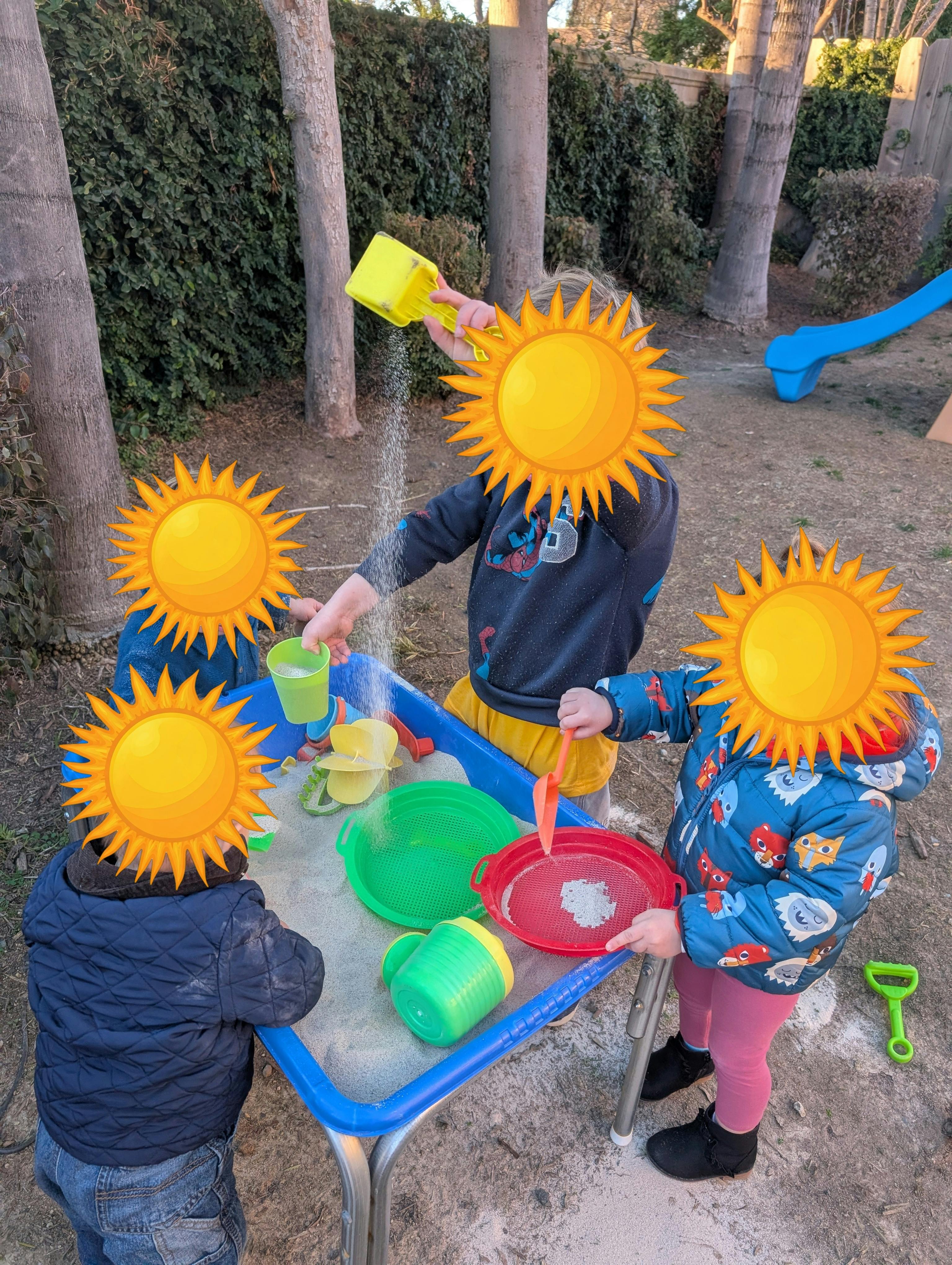 Children playing with sand and water at a table