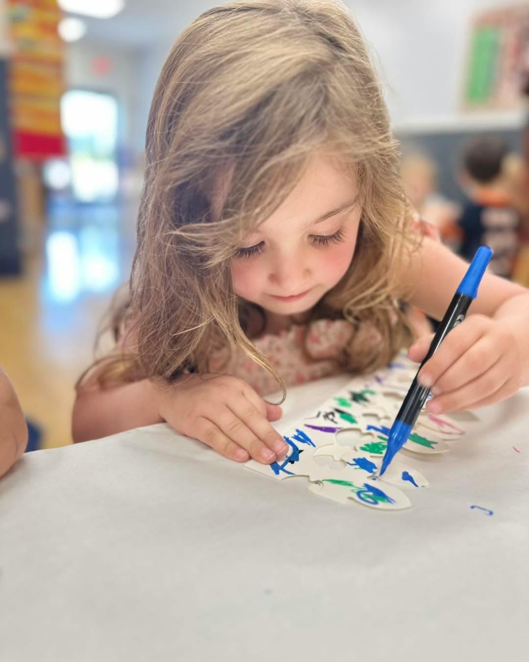 Child coloring on a paper stencil at a table