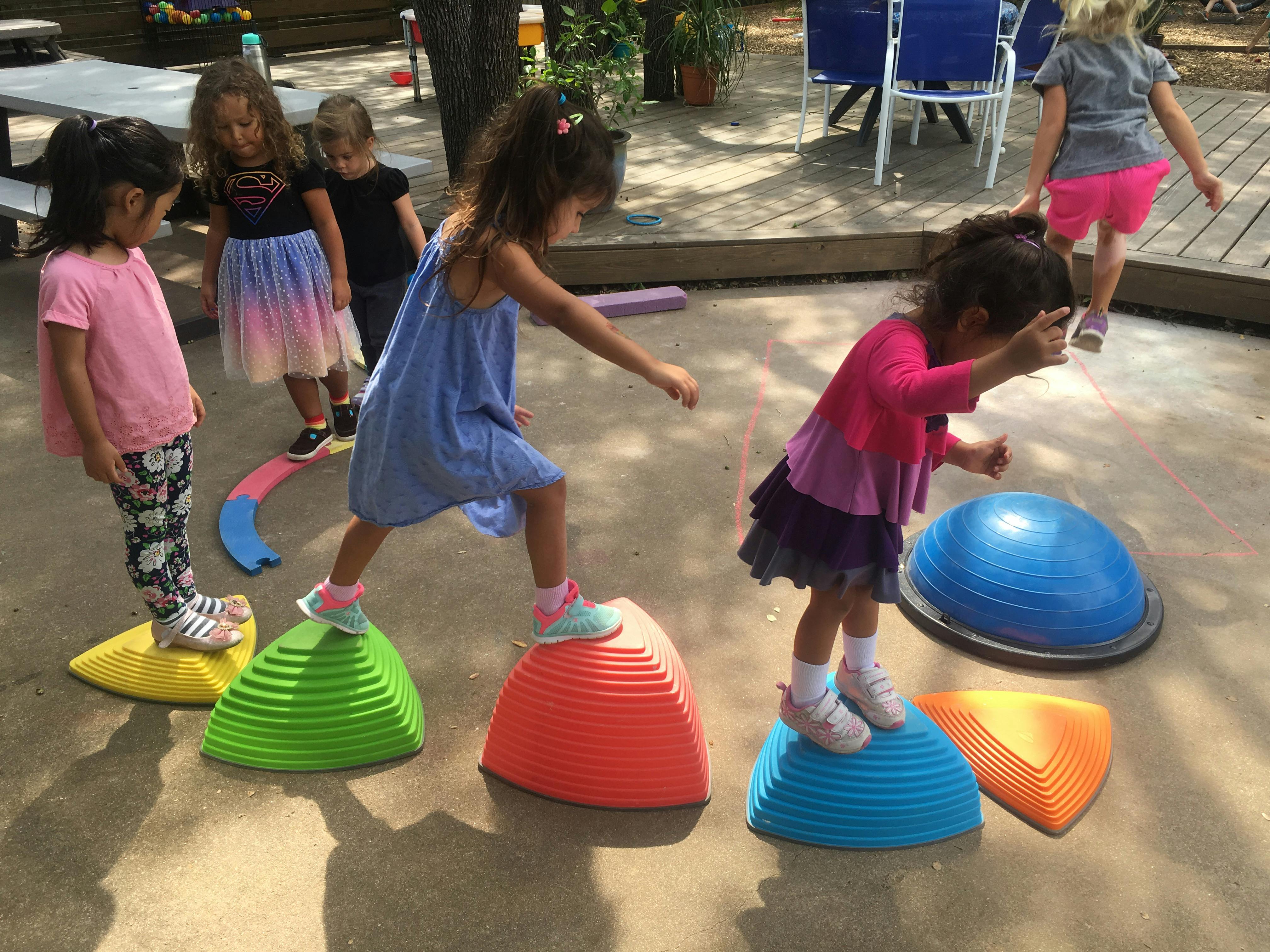 Children balancing on colorful dome-shaped stepping stones