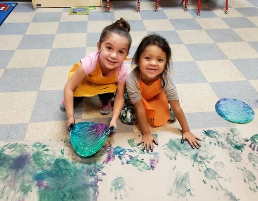 Two children finger painting on the floor