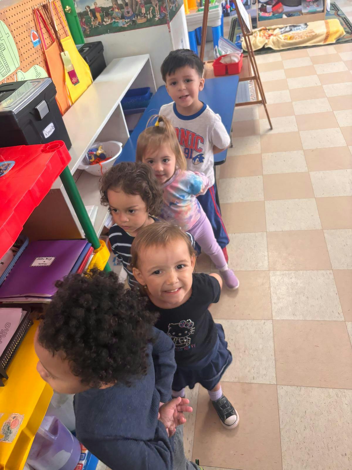 Five children standing in a line in a classroom