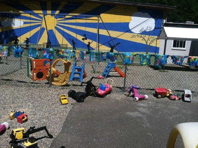 Playground with various toys and a fence in front of a painted wall