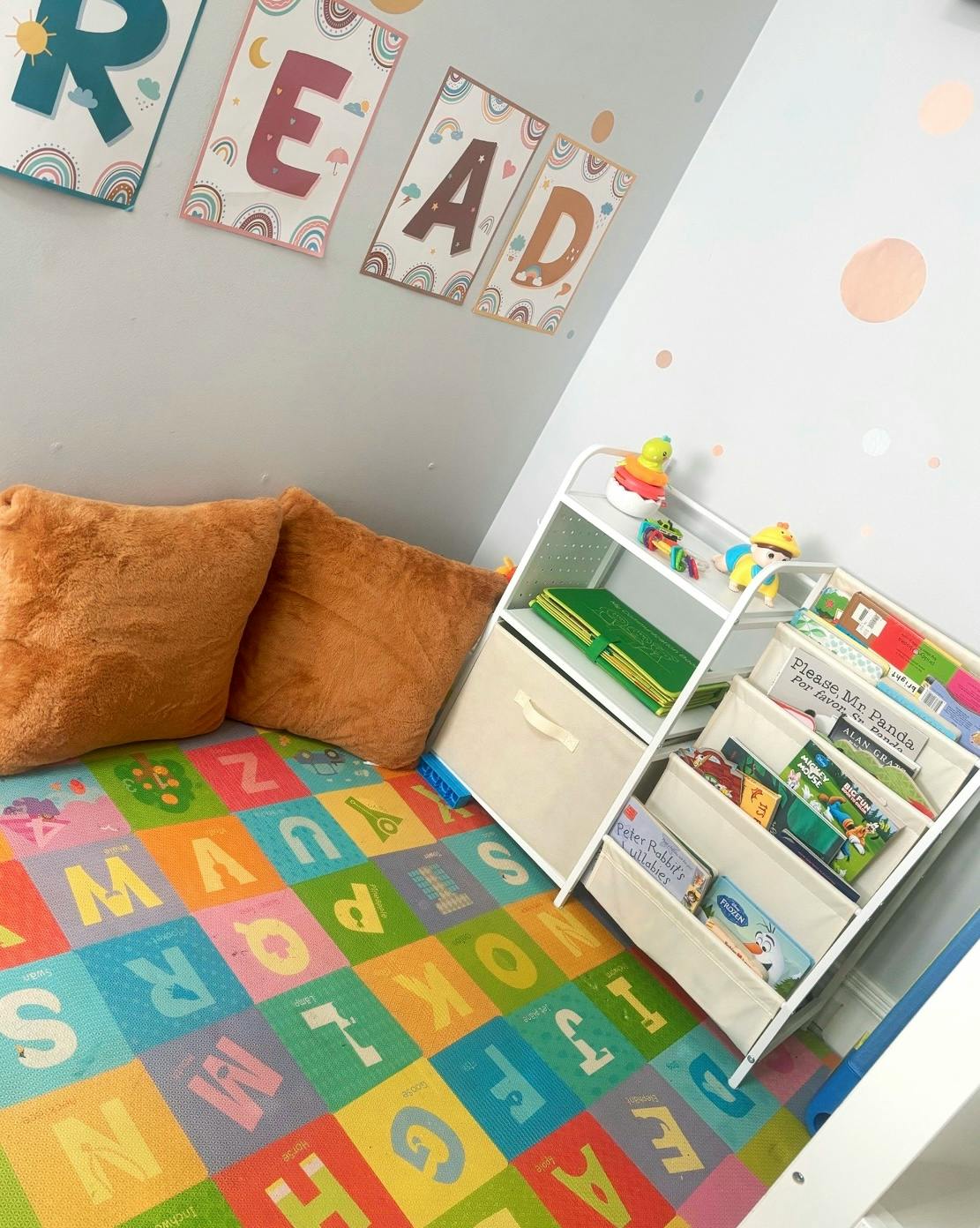 Children's room with alphabet mat, pillows, and bookshelf with books
