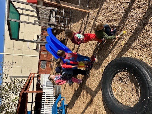 Children playing on a slide and playground structure