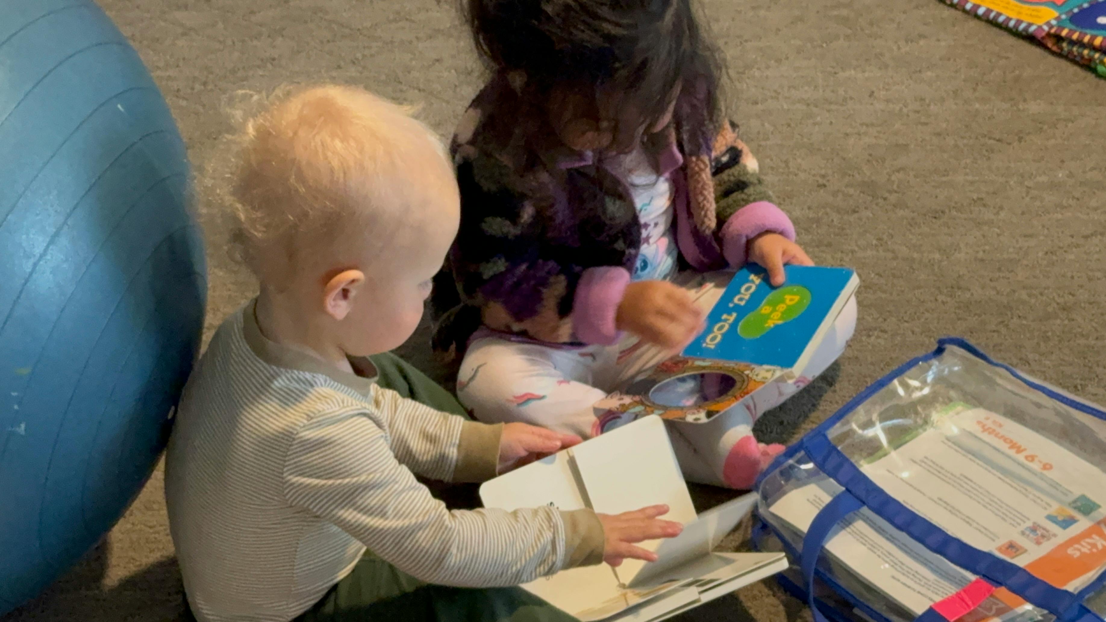 Two children sitting on the floor looking at books