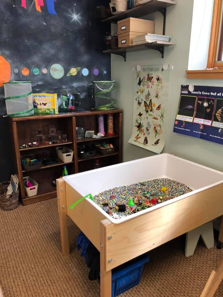 Sensory table filled with small colorful objects in a classroom