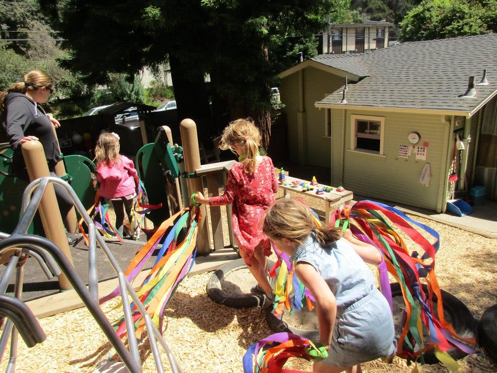Adult and children playing outdoors with colorful ribbons