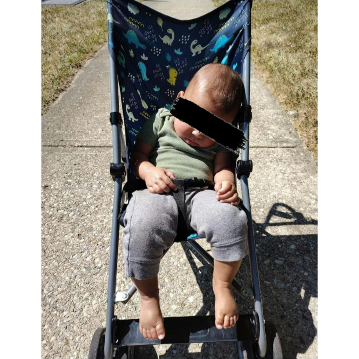 Child sitting in a stroller with a dinosaur pattern
