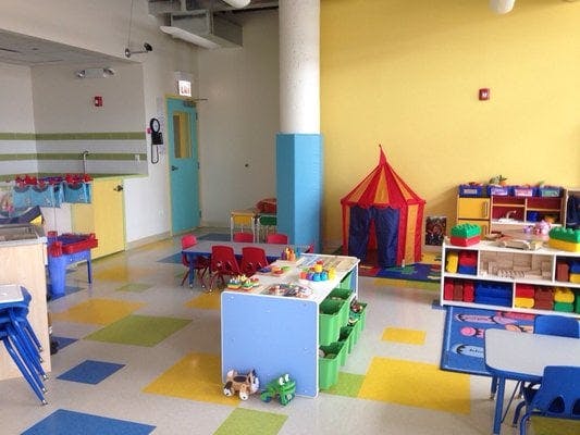 Colorful classroom with small tables, chairs, and a play tent