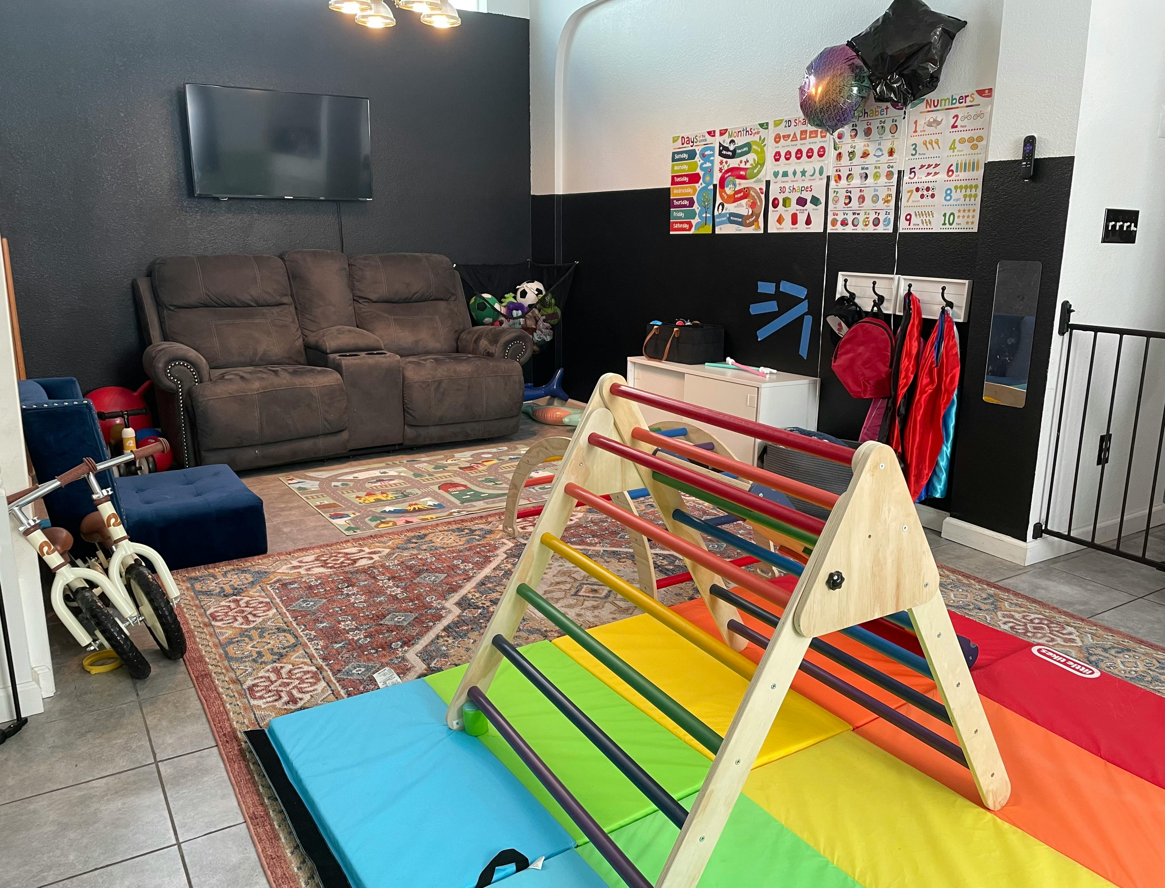 Indoor play area with a wooden climbing frame on colorful mats