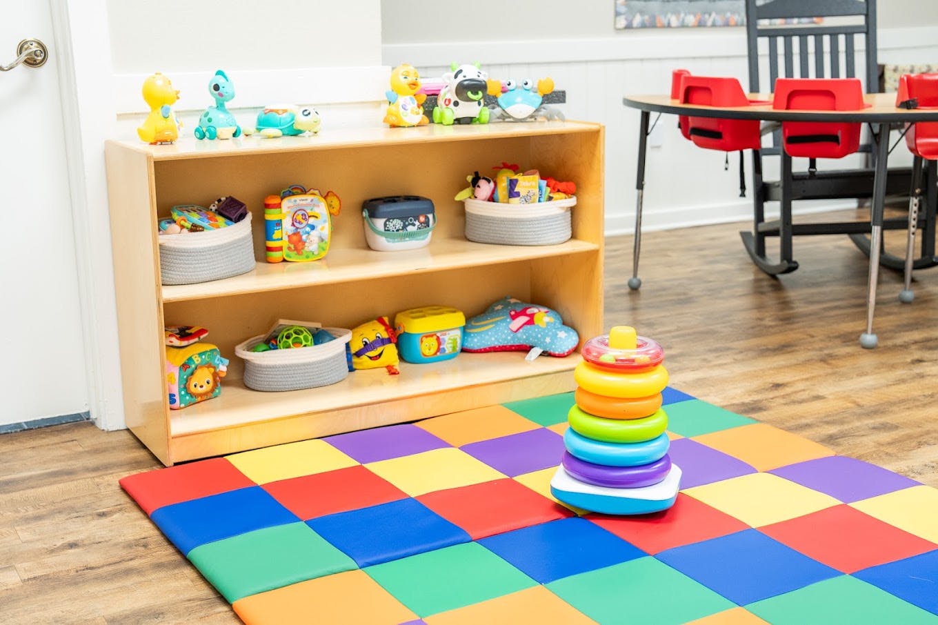 Wooden toy shelf and a plastic ring stacker on a colorful floor mat