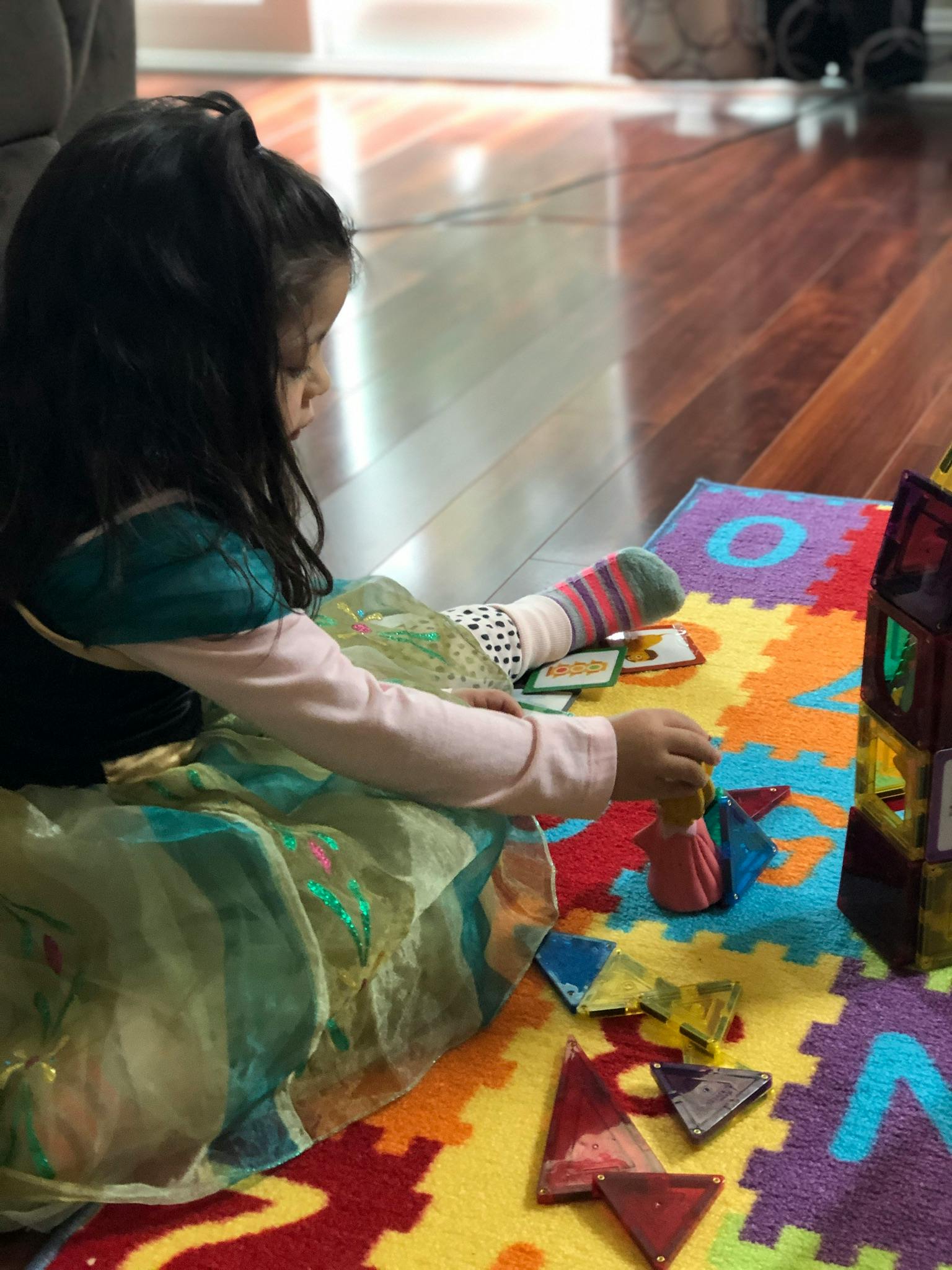 Child playing with magnetic tiles on a colorful mat