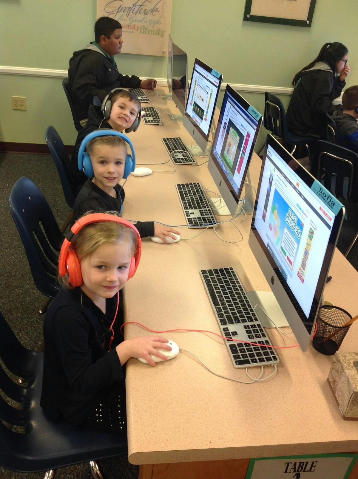 Children wearing headphones using computers in a classroom