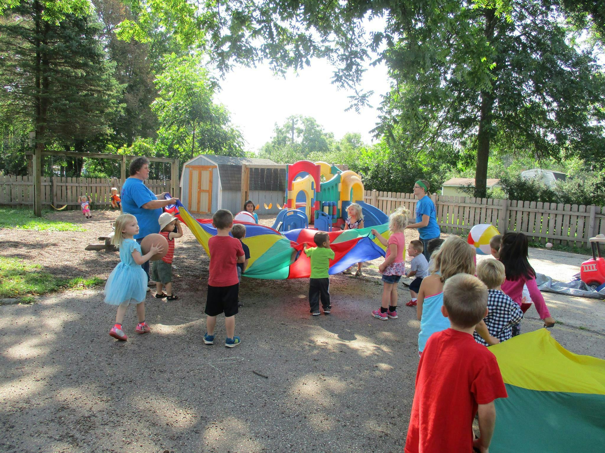 Adult and children playing with a colorful parachute outdoors