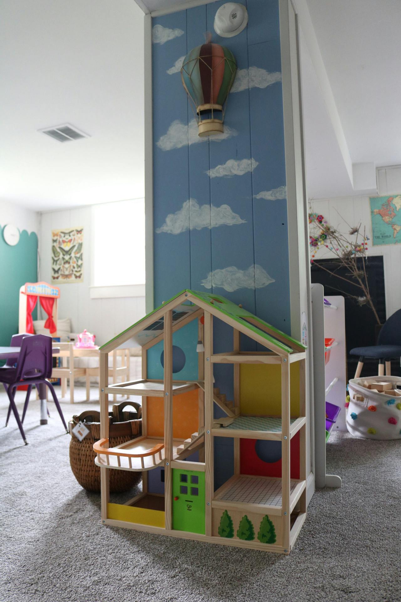 Dollhouse in a playroom with a hot air balloon wall decoration