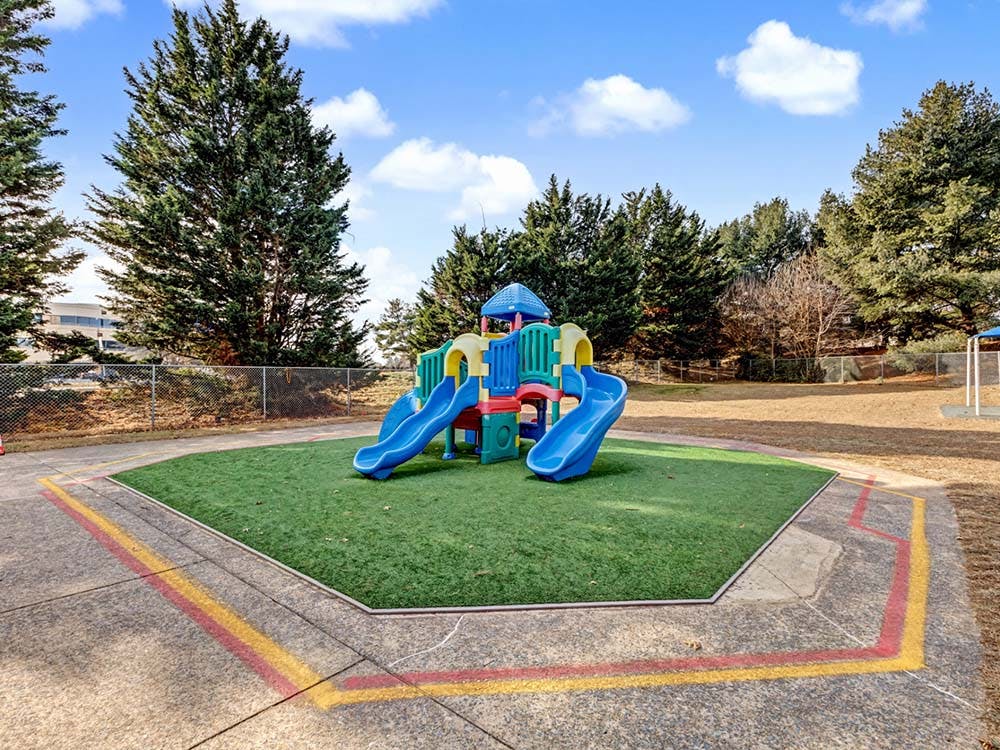 Colorful playground structure with two blue slides on artificial turf