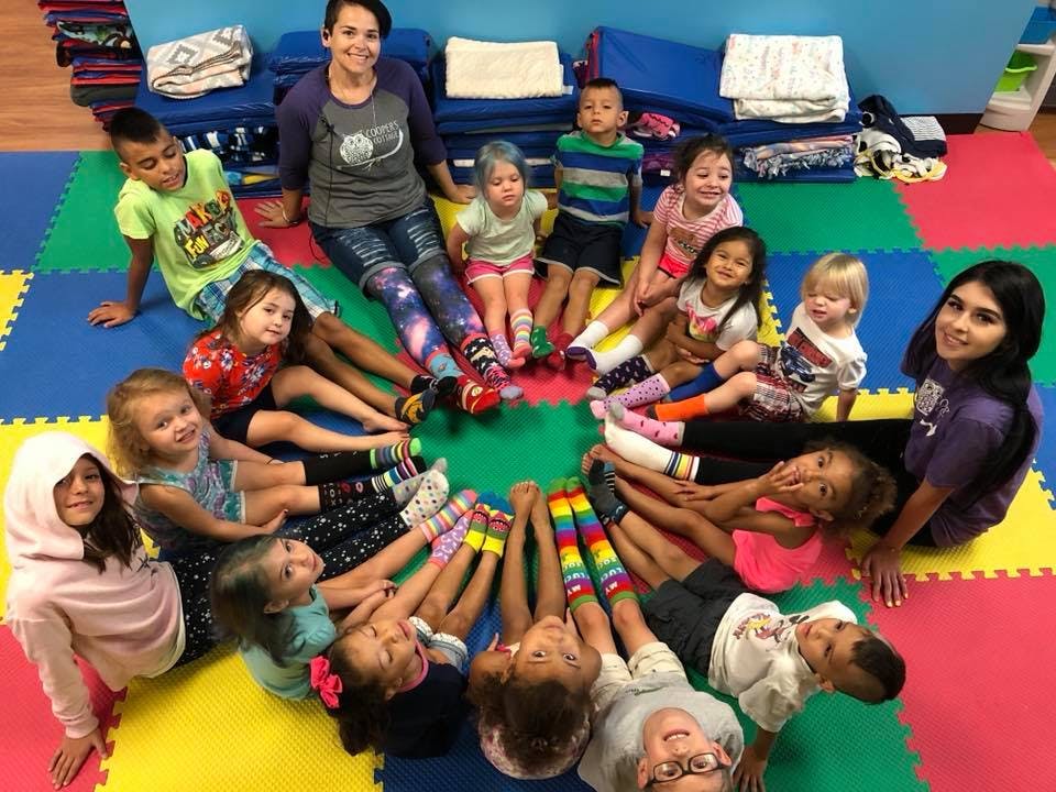 Adults and children sitting in a circle on a colorful mat