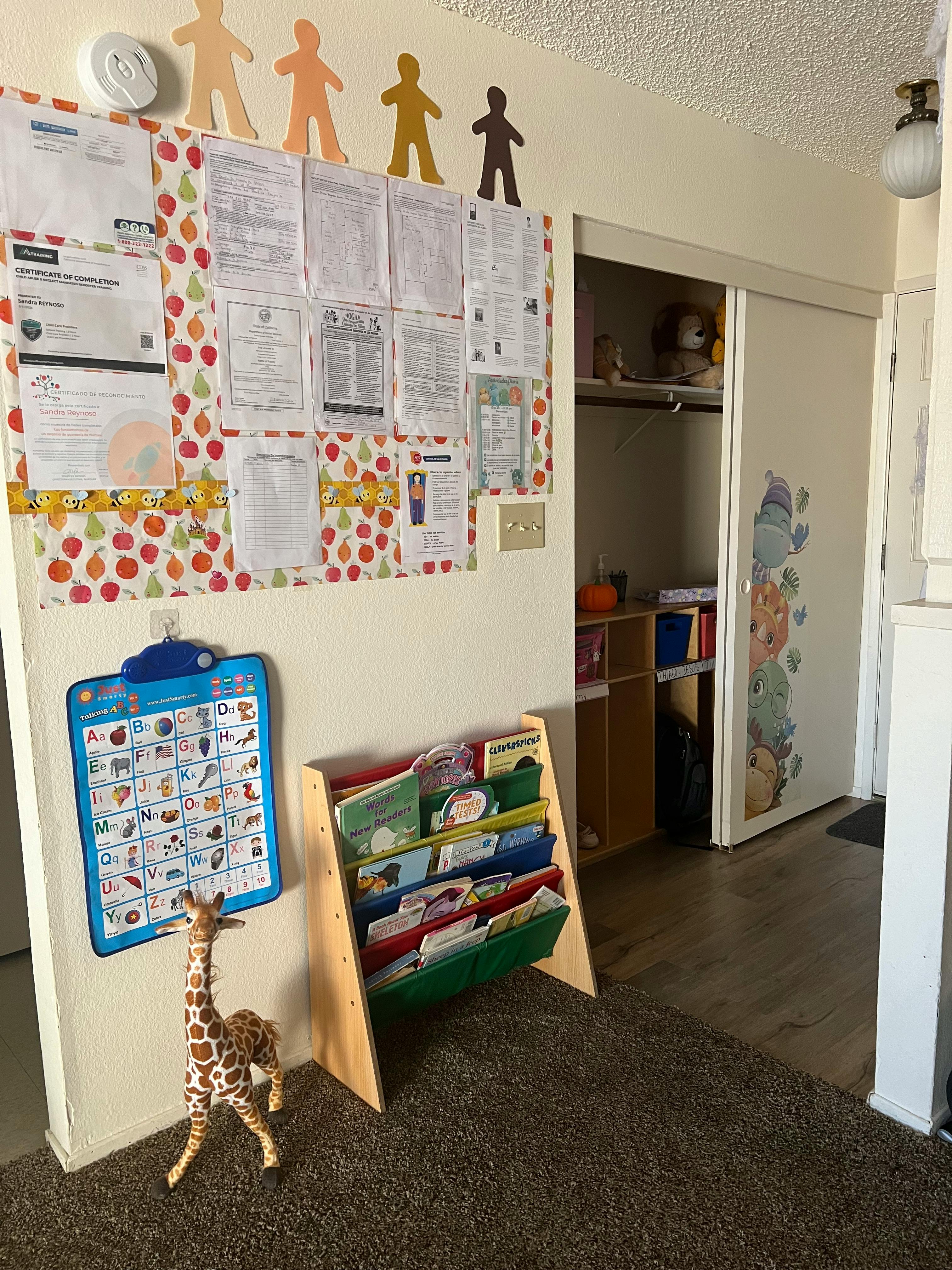 Bulletin board with papers, a book display, and a giraffe toy