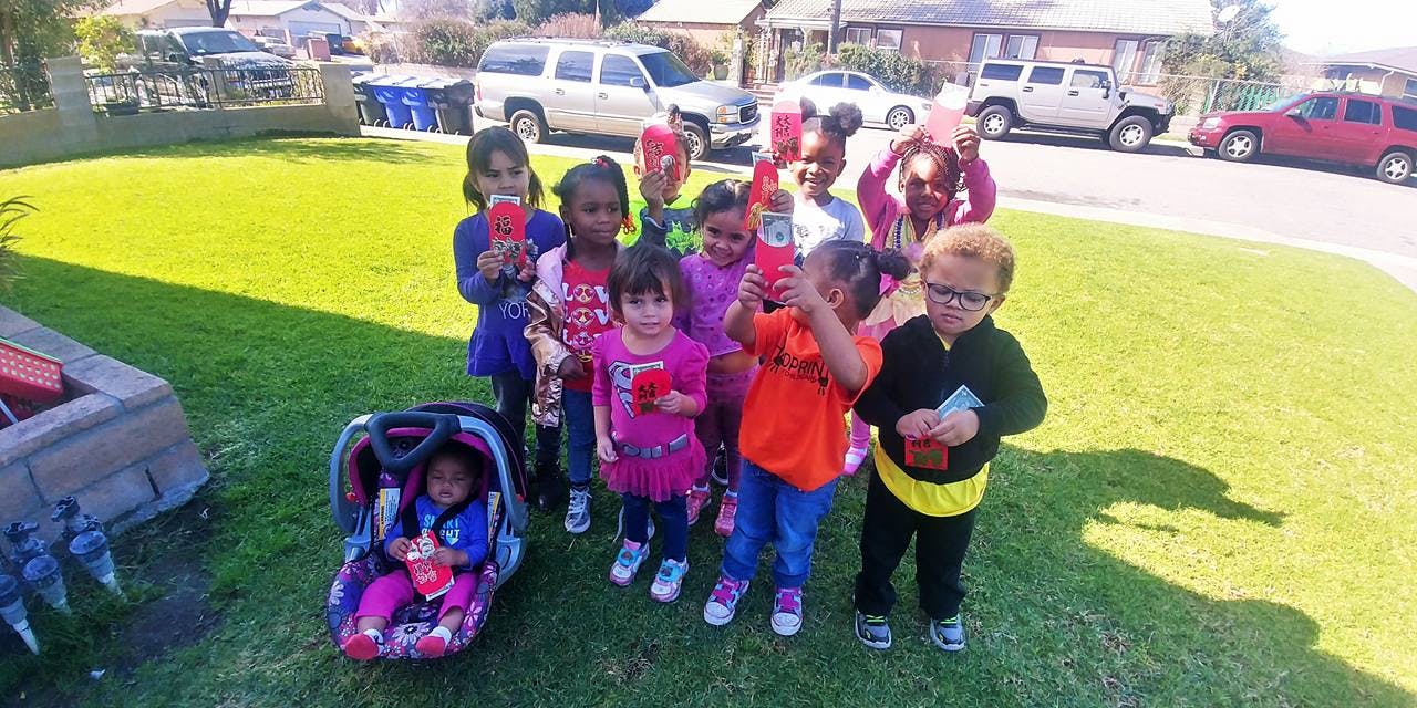 Group of children standing on grass, some holding items