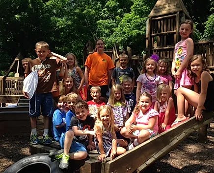 Group of children and adults posing outdoors on playground equipment