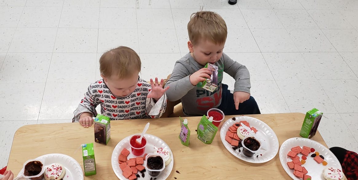Two children at a table with plates of food and drinks