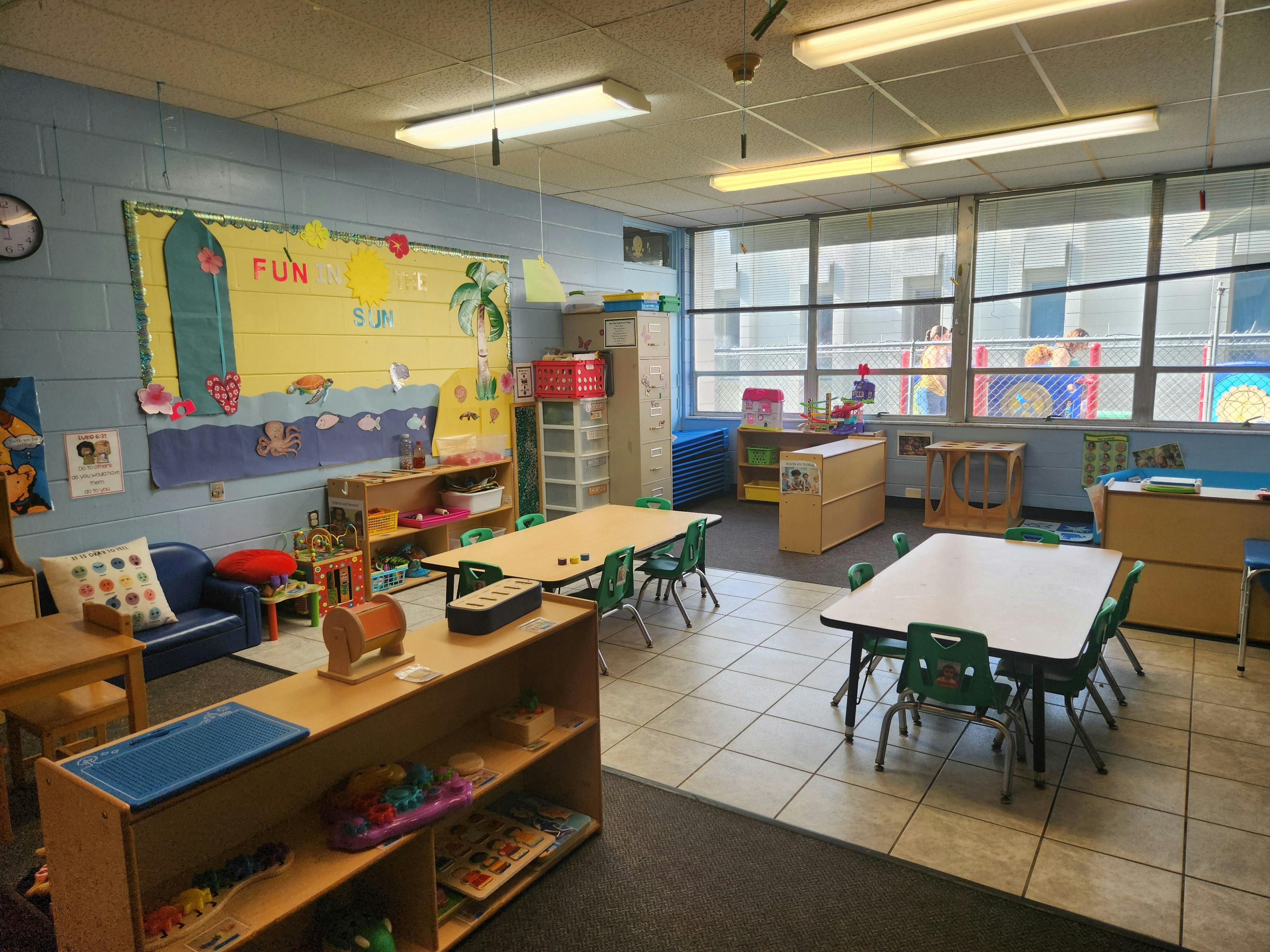 Classroom with tables, chairs, and a bulletin board