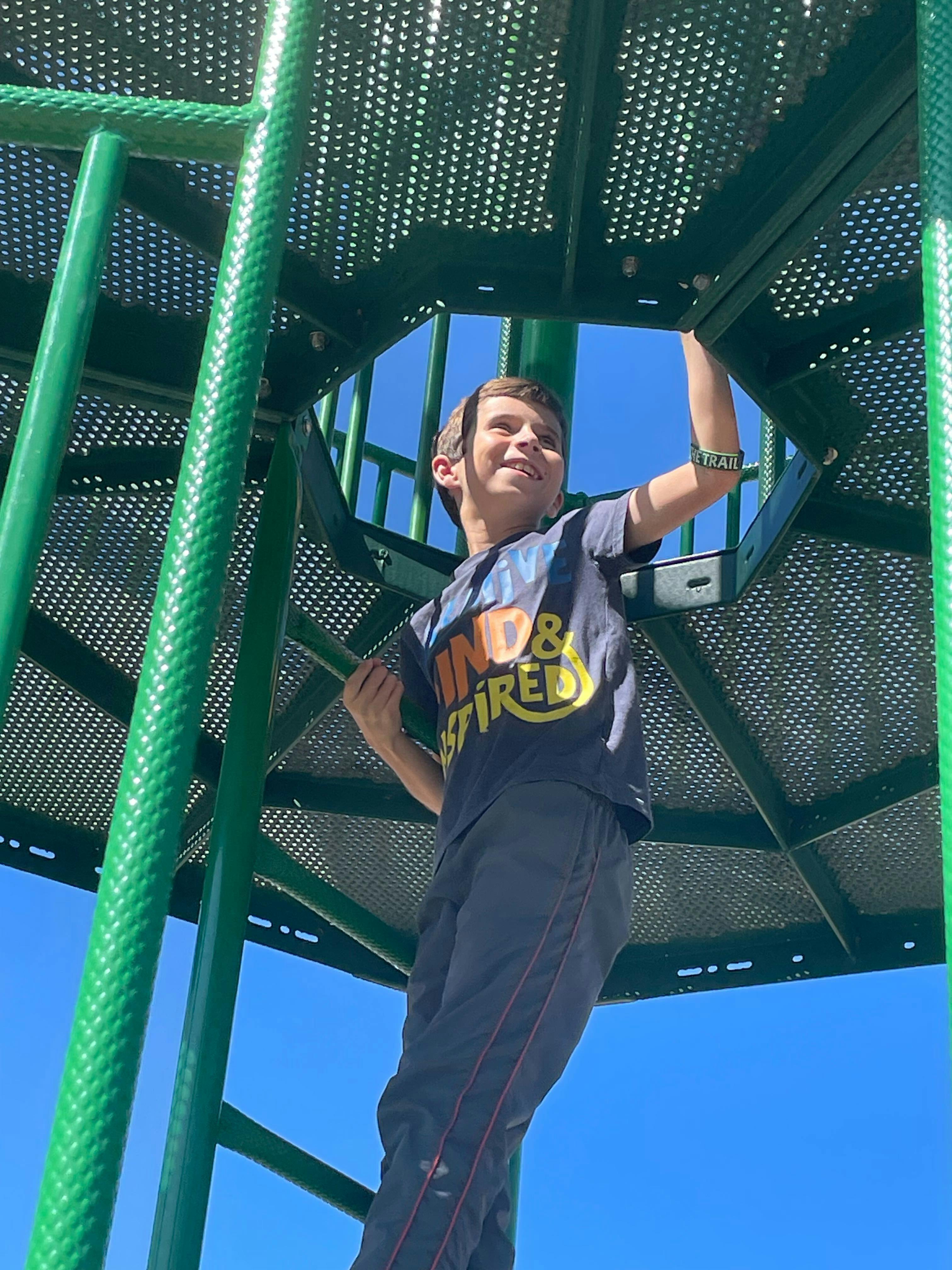 Child climbing on a green playground structure